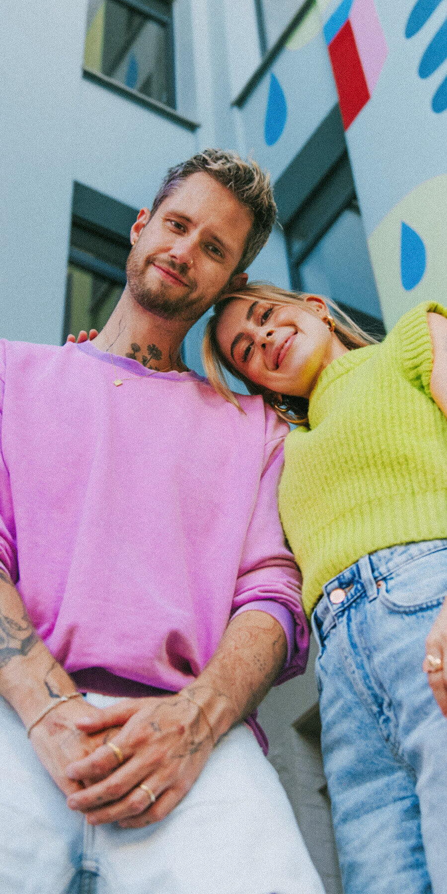 DJ duo kitsch and SASH standing together in a colorful urban setting, smiling